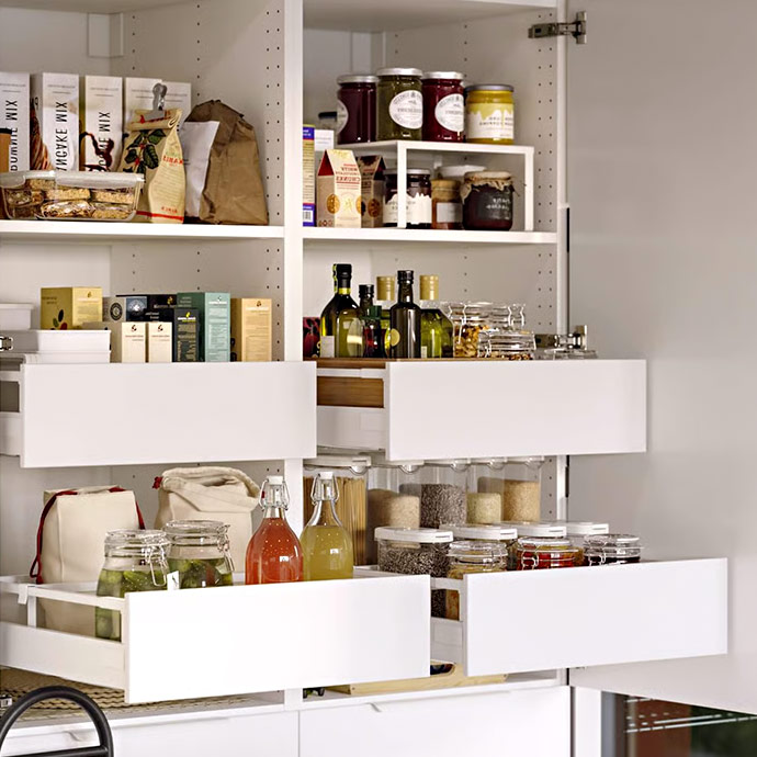Despensa organizada con estantes blancos, cajones extraíbles, botes de cristal, botellas de aceite y legumbres.