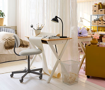 One side of a shared bedroom with a BOLLPOJKE desk in white/pine and chair by a bed, separated by light curtains.