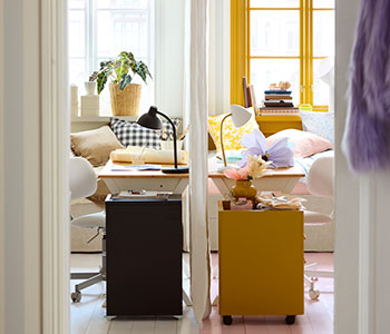 Two BOLLPOJKE pine/white desks side by side in a shared bedroom with one side styled neutral and the other more colourful.