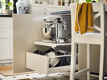 Armario de cocina blanco abierto con estantes extraíbles que guardan una batidora y una cafetera, optimizando el espacio para electrodomésticos.