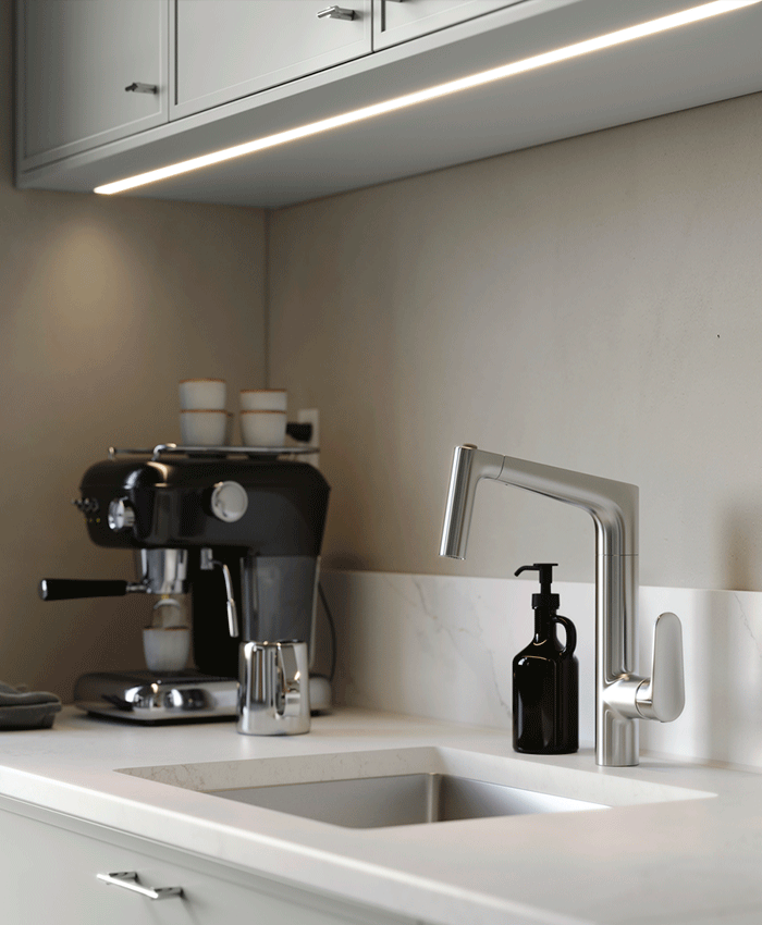 Under-cabinet LED lighting illuminating a white marble countertop with a stainless steel sink and faucet. A coffee machine and soap dispenser sit in the background.