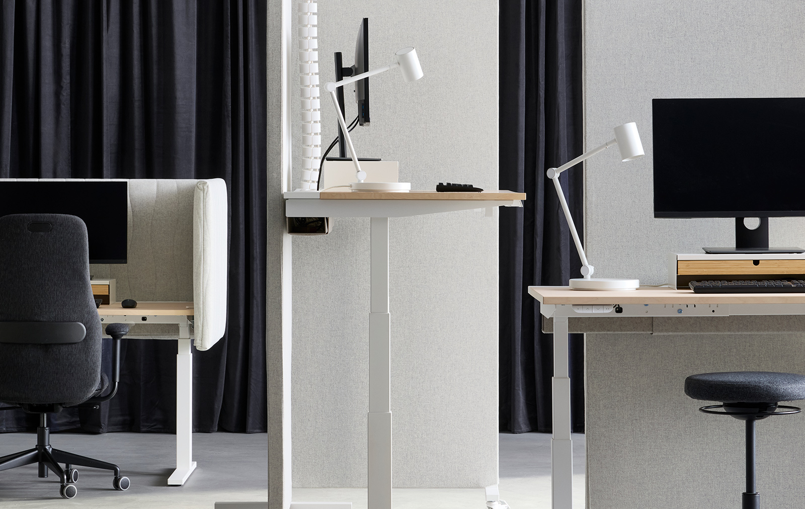 Espacio de oficina con estaciones de trabajo de escritorio ajustable (sentado/de pie), separadas por pantallas acústicas MITTZON en color beige‑blanco, con tela Gunnared.
