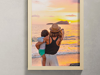 Framed photograph of a woman holding a child while watching the sunset over the sea with an island on the far horizon.