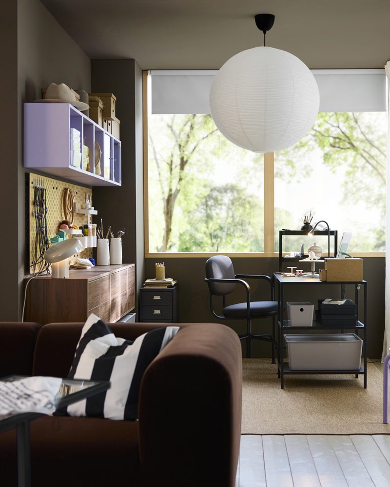 Espacio de trabajo compartido con un escritorio VITTSJÖ marrón oscuro con superficie de cristal, una silla, cajas de almacenamiento y una lámpara.