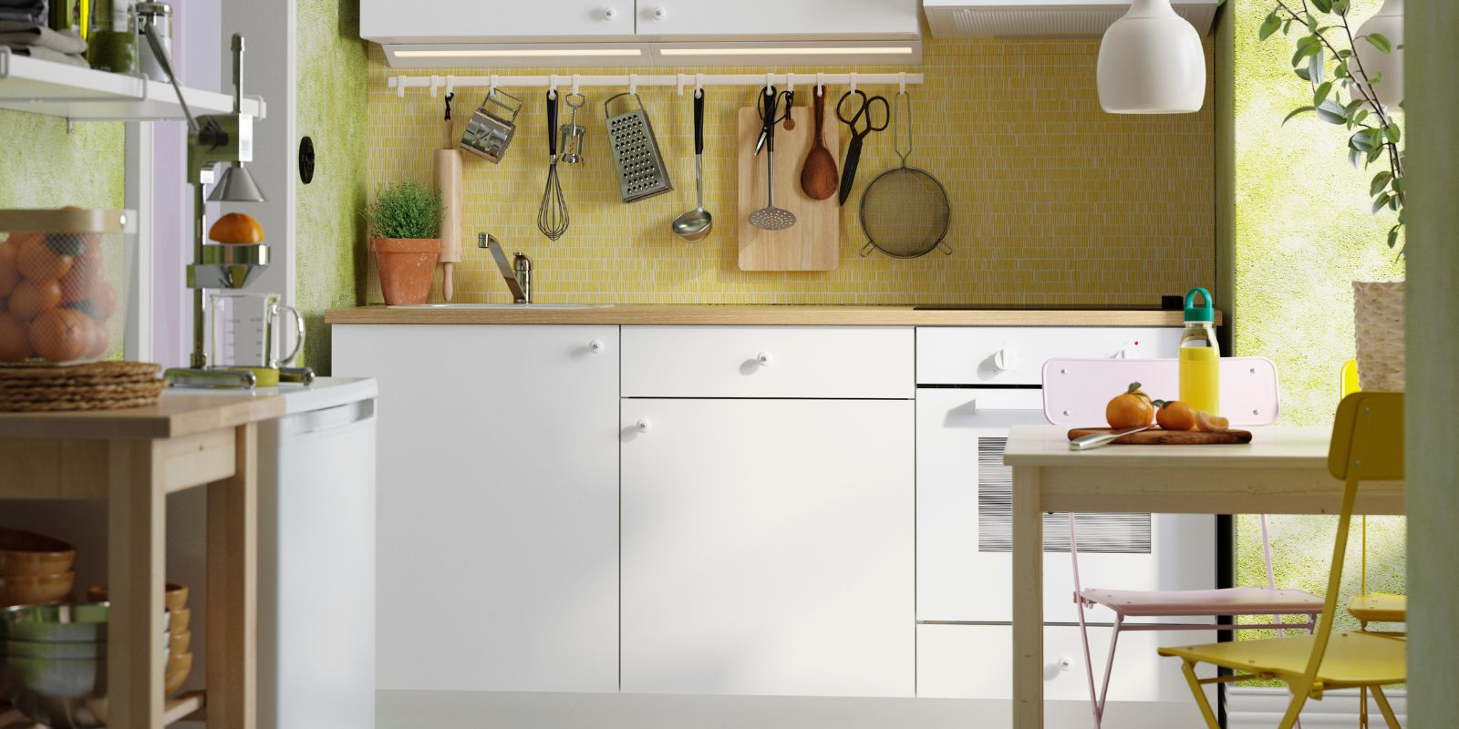 Cocina luminosa y compacta con gabinetes blancos, salpicadero de mosaico amarillo y luz natural. Los utensilios colgantes y las plantas aportan calidez y funcionalidad.
