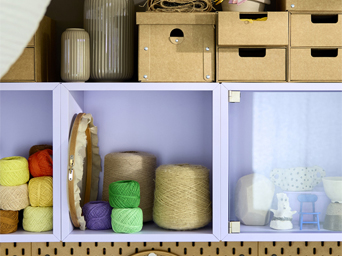 Close-up of EKET shelving unit in pale lilac, filled with colorful yarn, crafting supplies and multi-sized storage boxes.