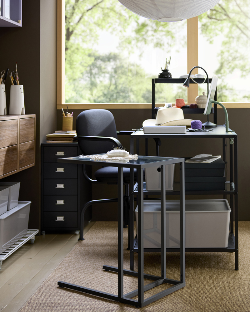 Espacio de trabajo en casa con un escritorio VITTSJÖ marrón oscuro, una silla y cajones de almacenamiento, situado junto a una ventana luminosa.