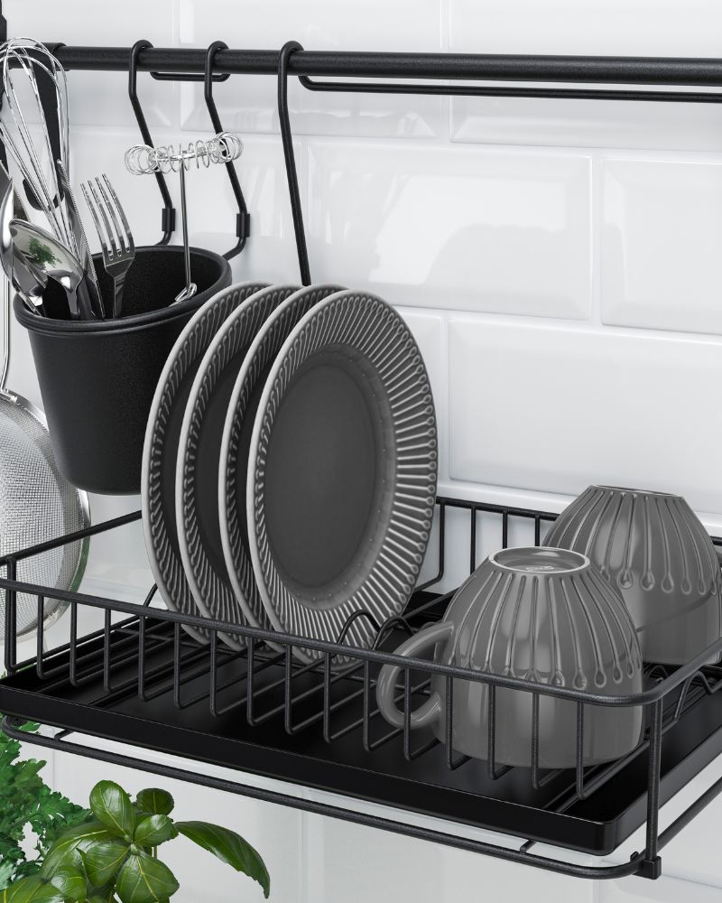 Escurridor HULTARP con cubiertos IKEA 365+, platos, tazas, colador y batidor en un estante metálico negro con ganchos y bandeja de goteo.