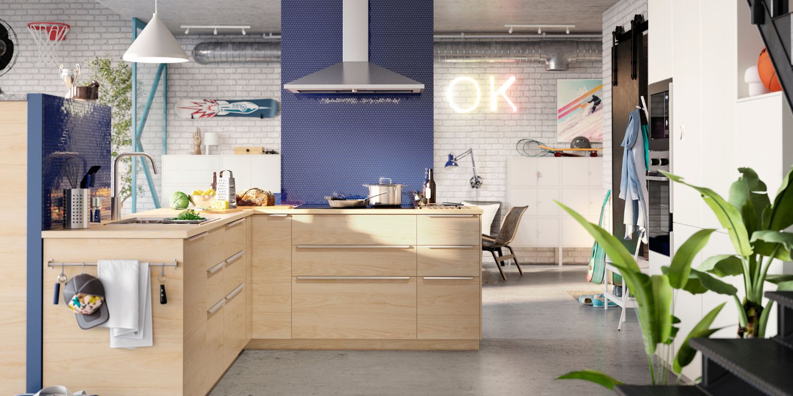 Modern kitchen with light wood cabinets, blue accent wall, central island, and metallic range hood. White bricks and illuminated "OK" sign.