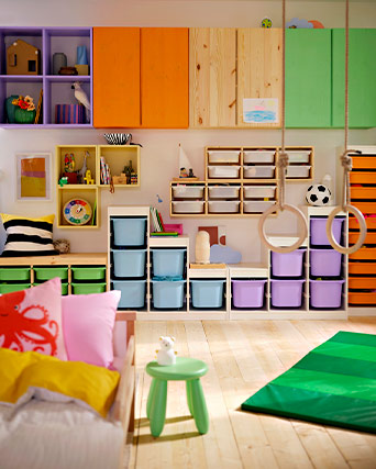 Play area with colorful modular storage, removable bins, and hanging gym rings. A tidy and vibrant space designed for creativity and active play.