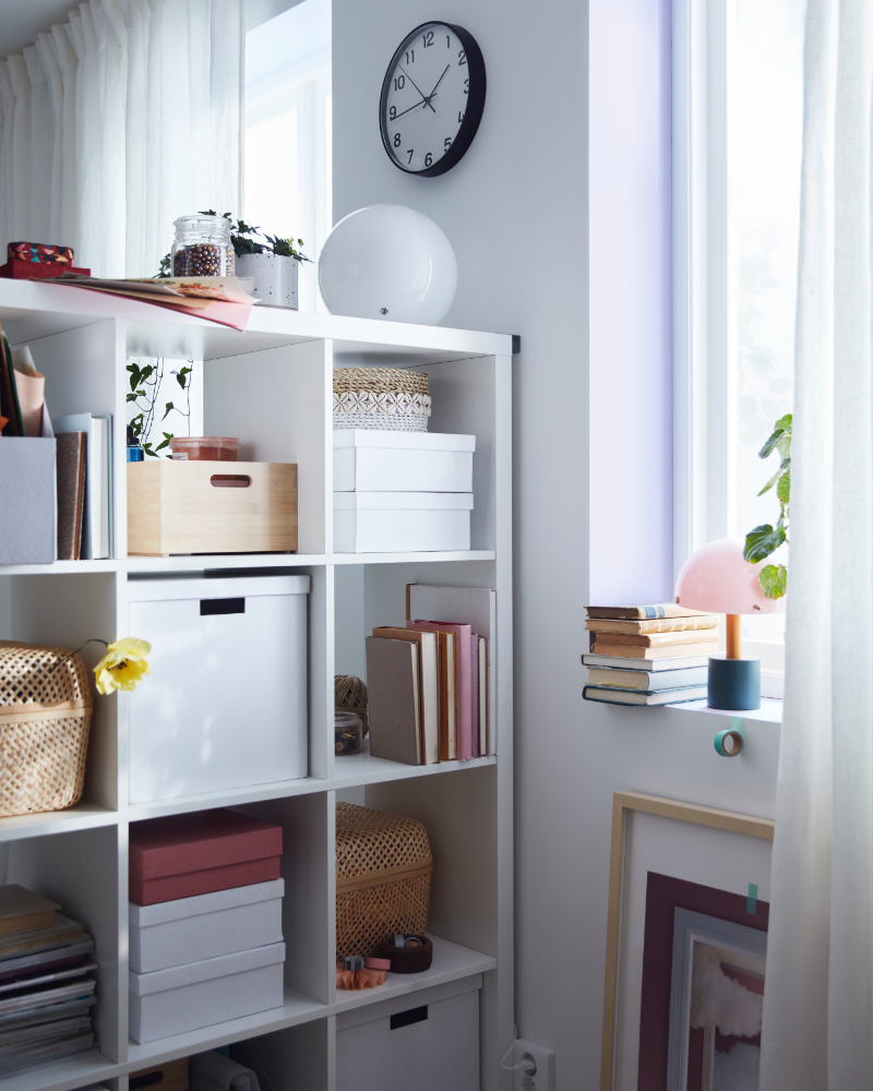 Habitación luminosa con la estantería KALLAX organizada con cajas, libros y decoración.