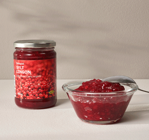 Bote de cristal de mermelada de arándanos rojos orgánicos SYLT LINGON junto a un pequeño cuenco de vidrio lleno de mermelada y una cuchara.