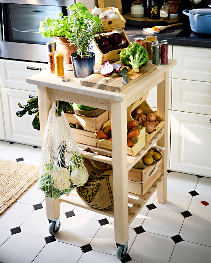 Light wood kitchen trolley filled with fresh vegetables, herbs, and mesh bags. A mobile and natural solution for organizing everyday ingredients.