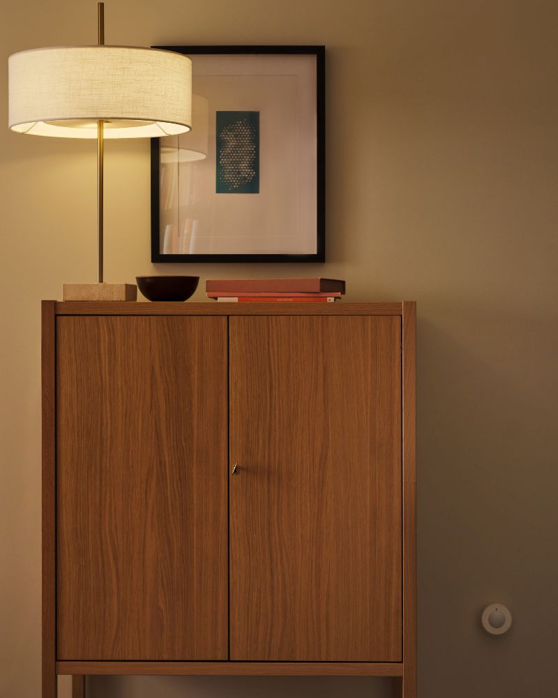 Se ha instalado un sensor de movimiento inalámbrico MYGGSPRAY en una pared cerca de un armario STOCKHOLM 2025 con dos puertas.