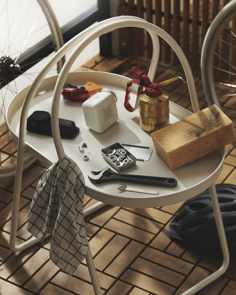 A close-up of a white MÅBÄRSSKÄR coffee table made for outdoor use, displaying hobby items like a sponge and a jar.