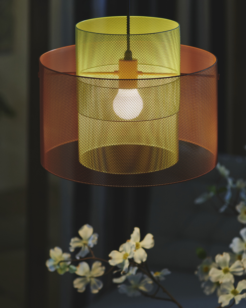 A balcony evening features a SOLVINDEN ceiling lamp in orange and light green mesh, illuminating a flower below.