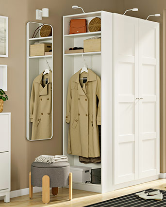 Entrada con armario blanco, espejo vertical, un puf gris y un abrigo beige colgado. Un diseño funcional y luminoso para organizar el recibidor.