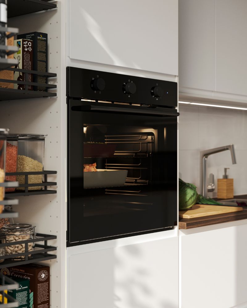 A black SPJUTBO fan oven is placed in a kitchen with matt white VOXTORP fronts and there’s food baking inside.