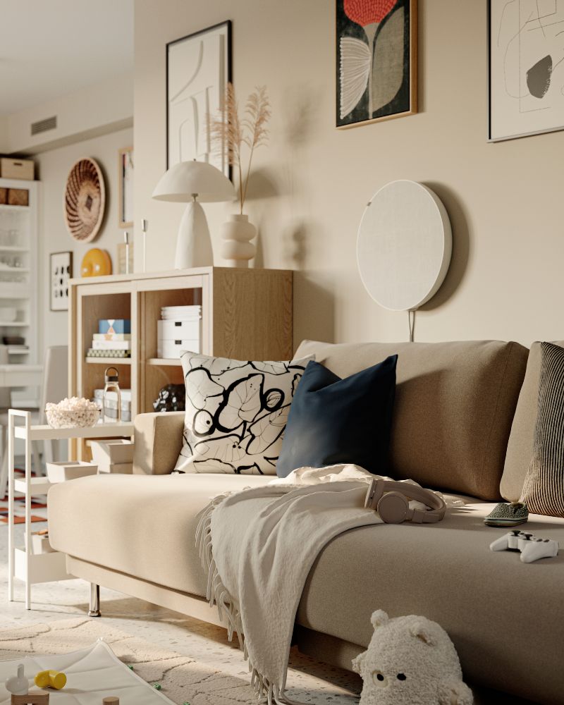 A GREJSIMOJS soft toy leans against an UPPÅKRA 3-seat modular sofa. A SOLSKYDD Bluetooth speaker is attached to the wall.