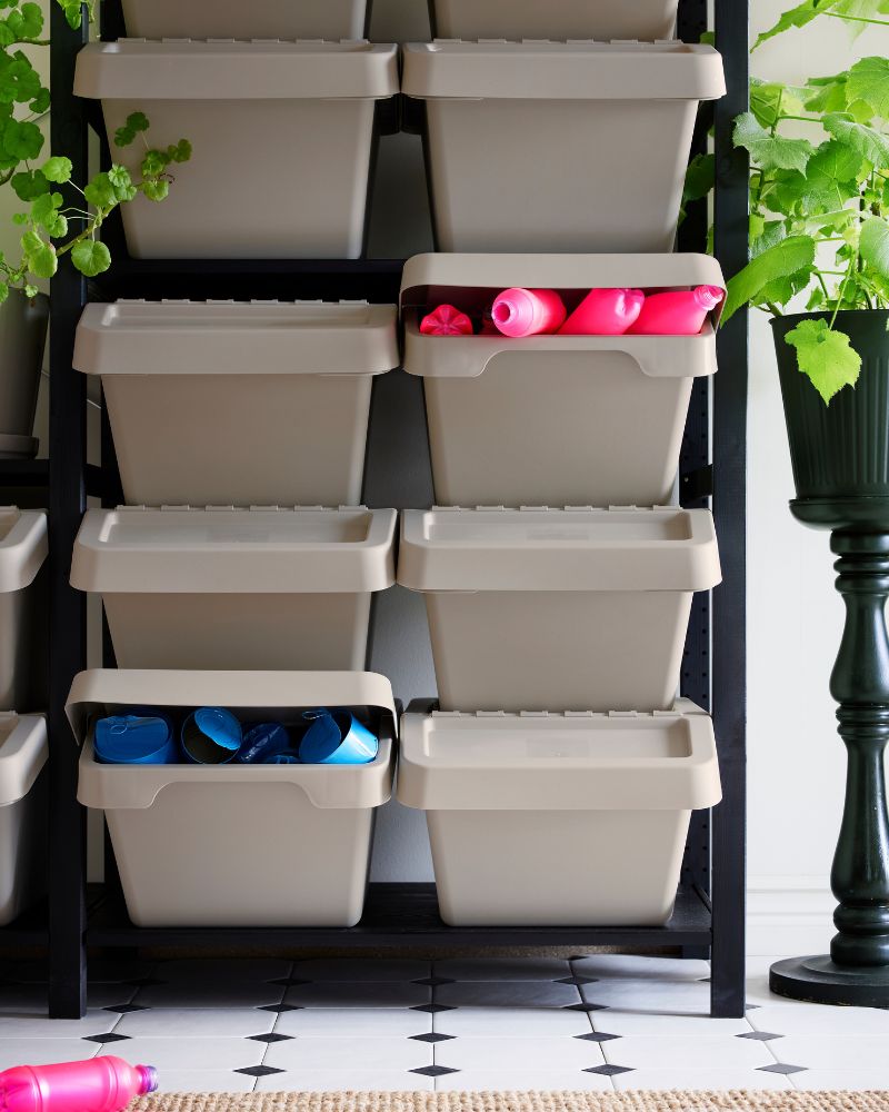 Shelves against the wall storing various items, with recycling bins neatly arranged at the bottom of the space.