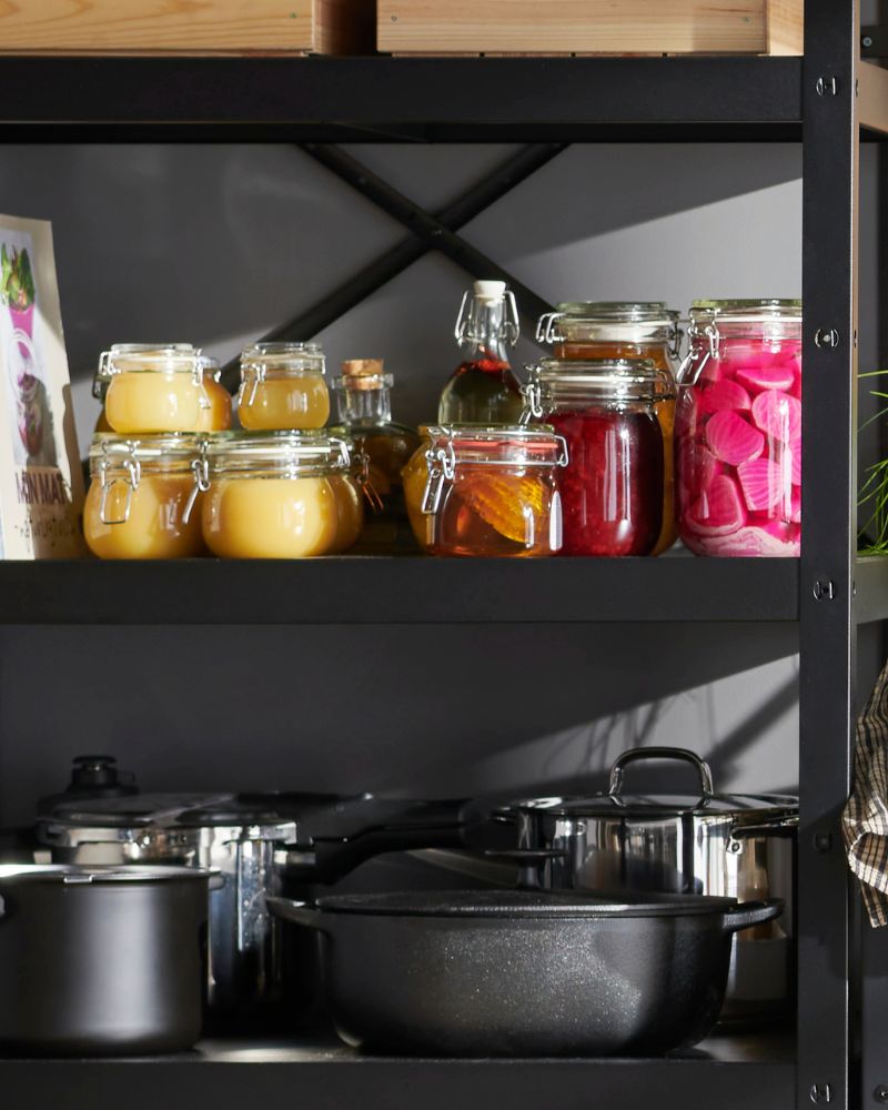 Metal shelf with neatly arranged canned goods; the setting suggests a food storage or preparation area.