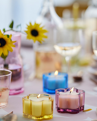 Velas coloridas en portavelas de cristal con forma de flor decoran una mesa festiva y primaveral.