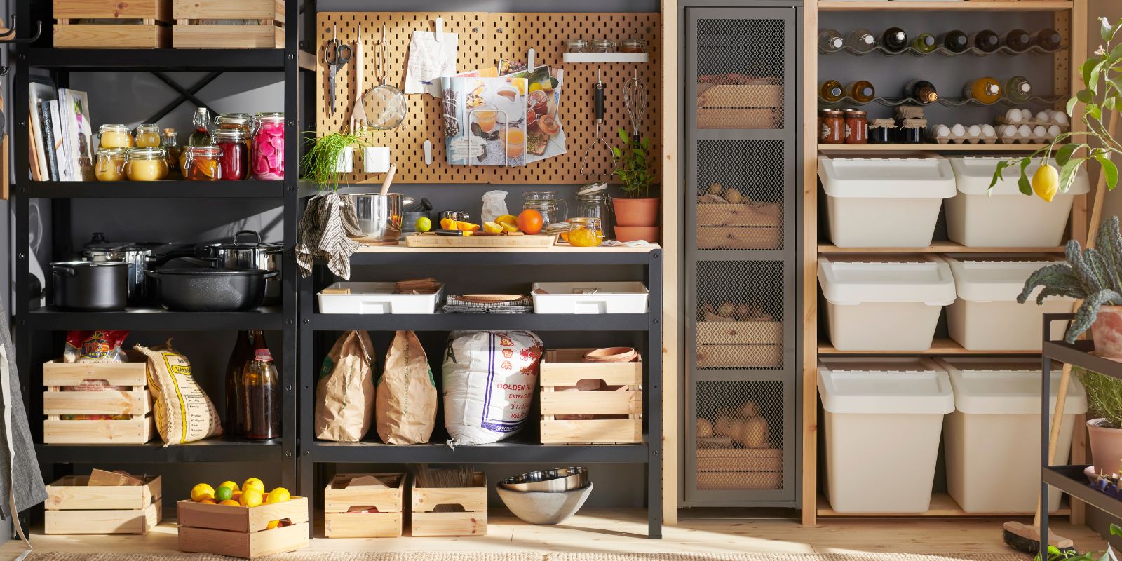 Storage area next to the kitchen with shelves, wooden boxes, hanging utensils on hooks, and recycling bins.