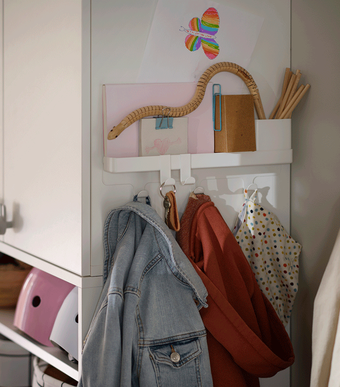 A hallway corner with a ALTARLIDEN hook rack with storage holding jackets, bags and small items on the side of a wardrobe.