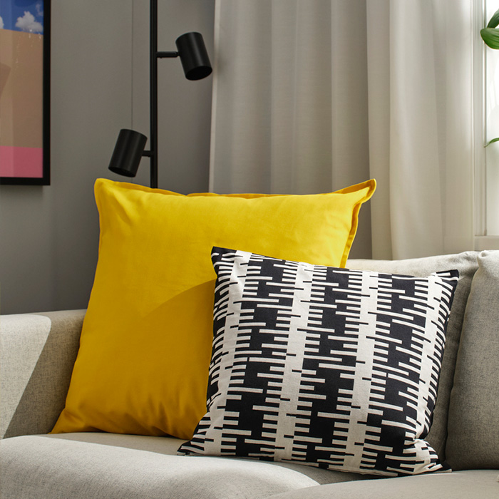Yellow and black-and-white cushions on a light grey sofa in a modern room.