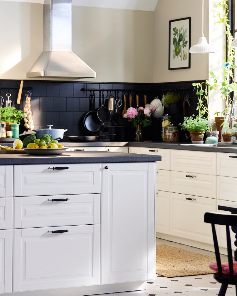 Una amplia cocina de estilo tradicional con frentes blancos BODBYN, que incluye una isla de cocina y un comedor de madera oscura.