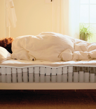 Person lying on a mattress with visible internal structure of individual pocket springs.