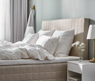 Elegant bed with upholstered headboard, quilted mattress, and white bedding in a modern bedroom.