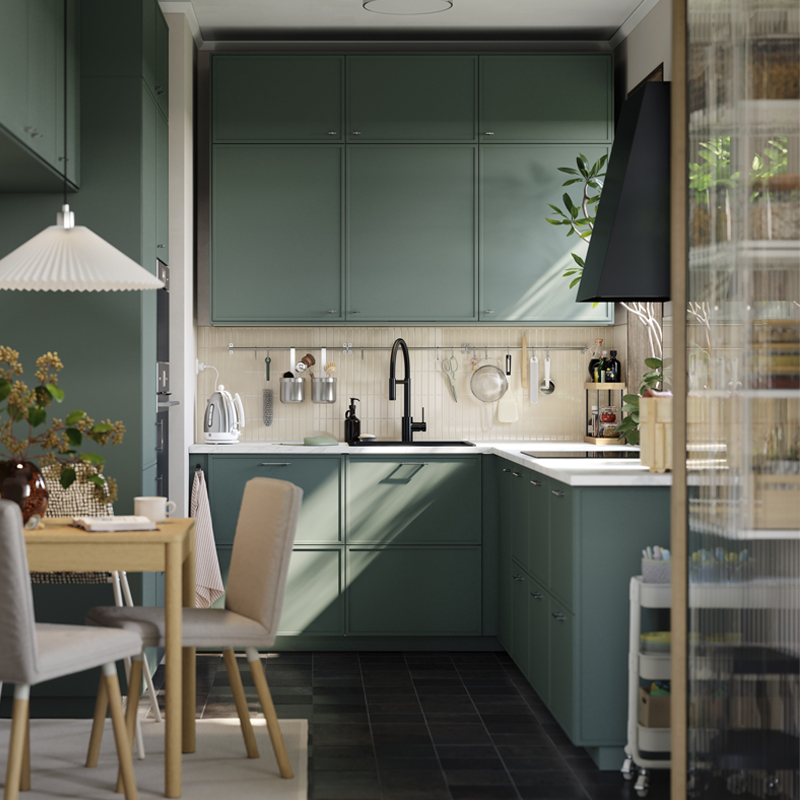 Una cocina pequeña cuenta con armarios bajos, altos y de encimera que llegan hasta el techo, y hay una mesita con una silla.