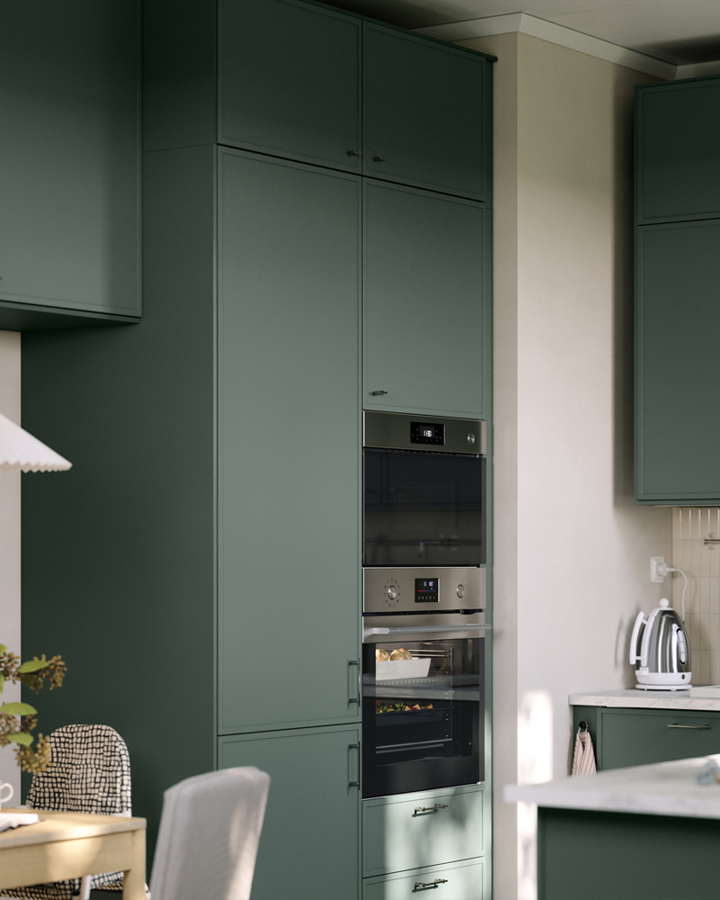 Un armario alto para electrodomésticos empotrados con puertas gris verdosas tiene un horno y un microondas integrados, con cajones debajo.