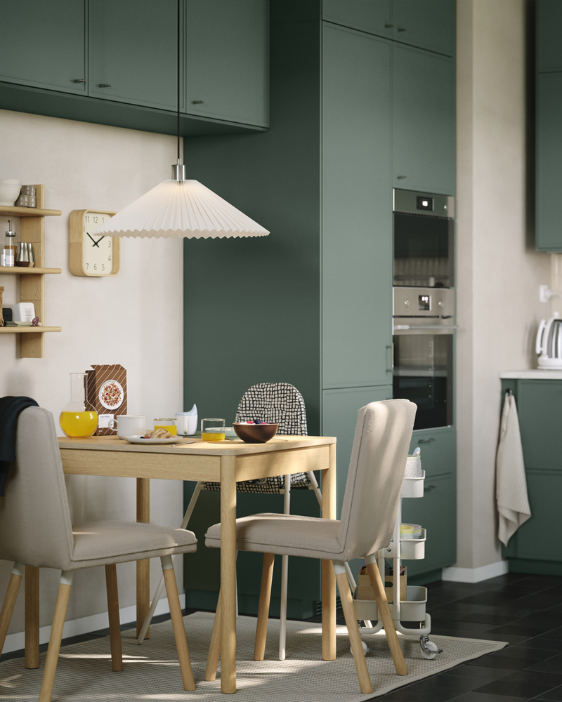 Una mesa extensible TONSTAD en chapa de roble con sillas tapizadas a juego se encuentra en un pequeño comedor dentro de la cocina.