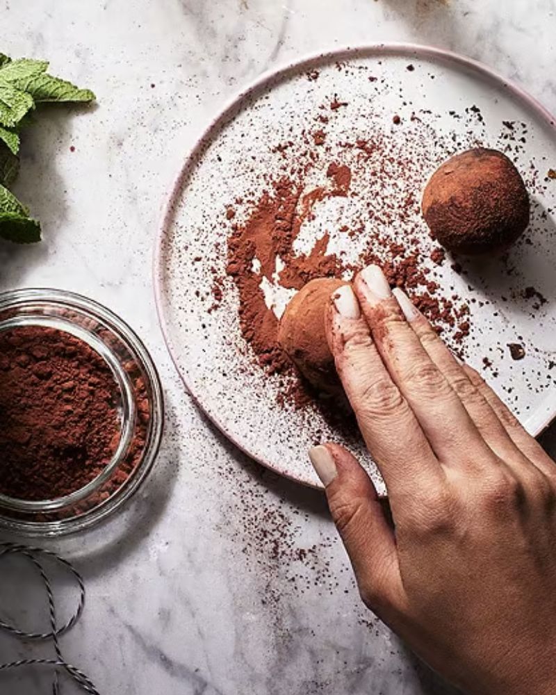 Trufa de chocolate en polvo de cacao en un plato de mármol. Menta fresca y más cacao cerca.
