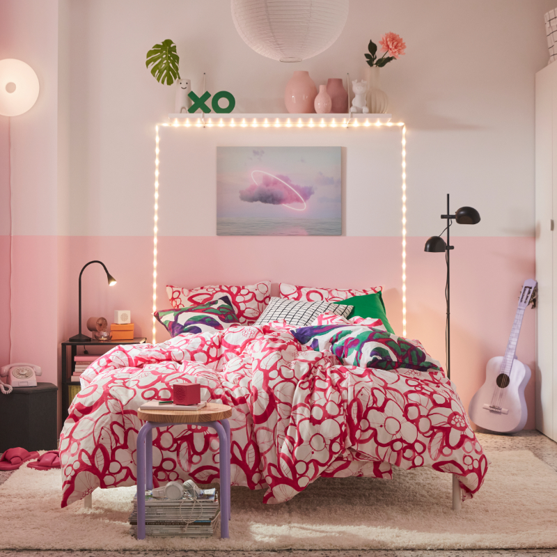 En este colorido dormitorio, la cama luce una funda nórdica y fundas de almohada HÄRLIR en blanco y rosa brillante con un estampado floral.