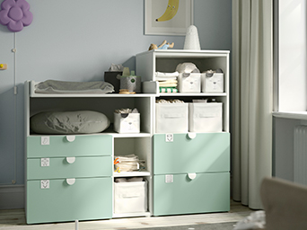 Cambiador con librería en color blanco y verde claro lleno de artículos para el cuidado del bebé