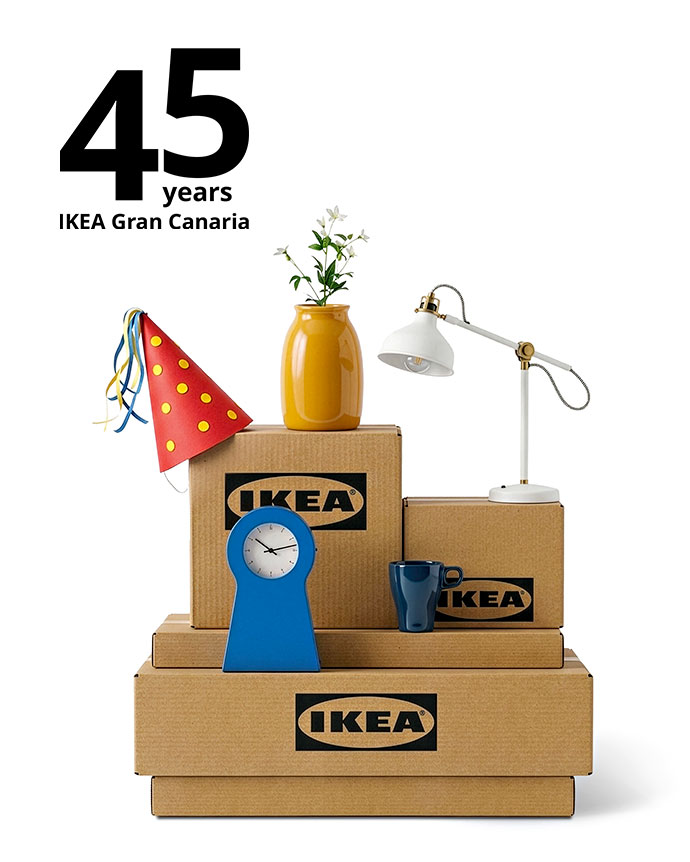 Stack of IKEA boxes with home items, a party hat, and "45 years IKEA Gran Canaria" text. A clean, festive composition on a bright white background.