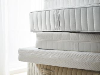 Stacked white mattresses showing different layers and textures in a minimalist setting.