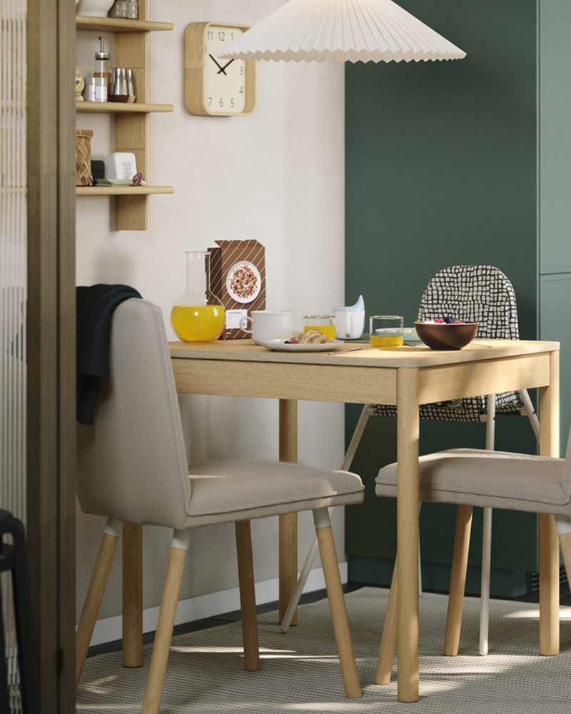A TONSTAD extendable table in oak veneer with matching upholstered chairs is standing in a small dining area in a kitchen.