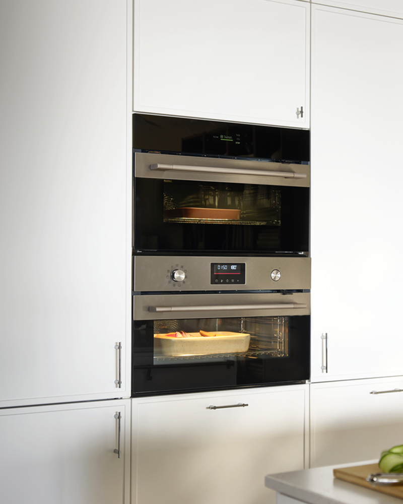 A high cabinet for built-in appliances with doors has an integrated oven and microwave, with drawers below.