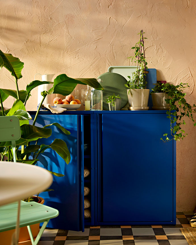 Cojín de exterior con rayas amarillas y blancas sobre una silla de madera en una terraza soleada con plantas.