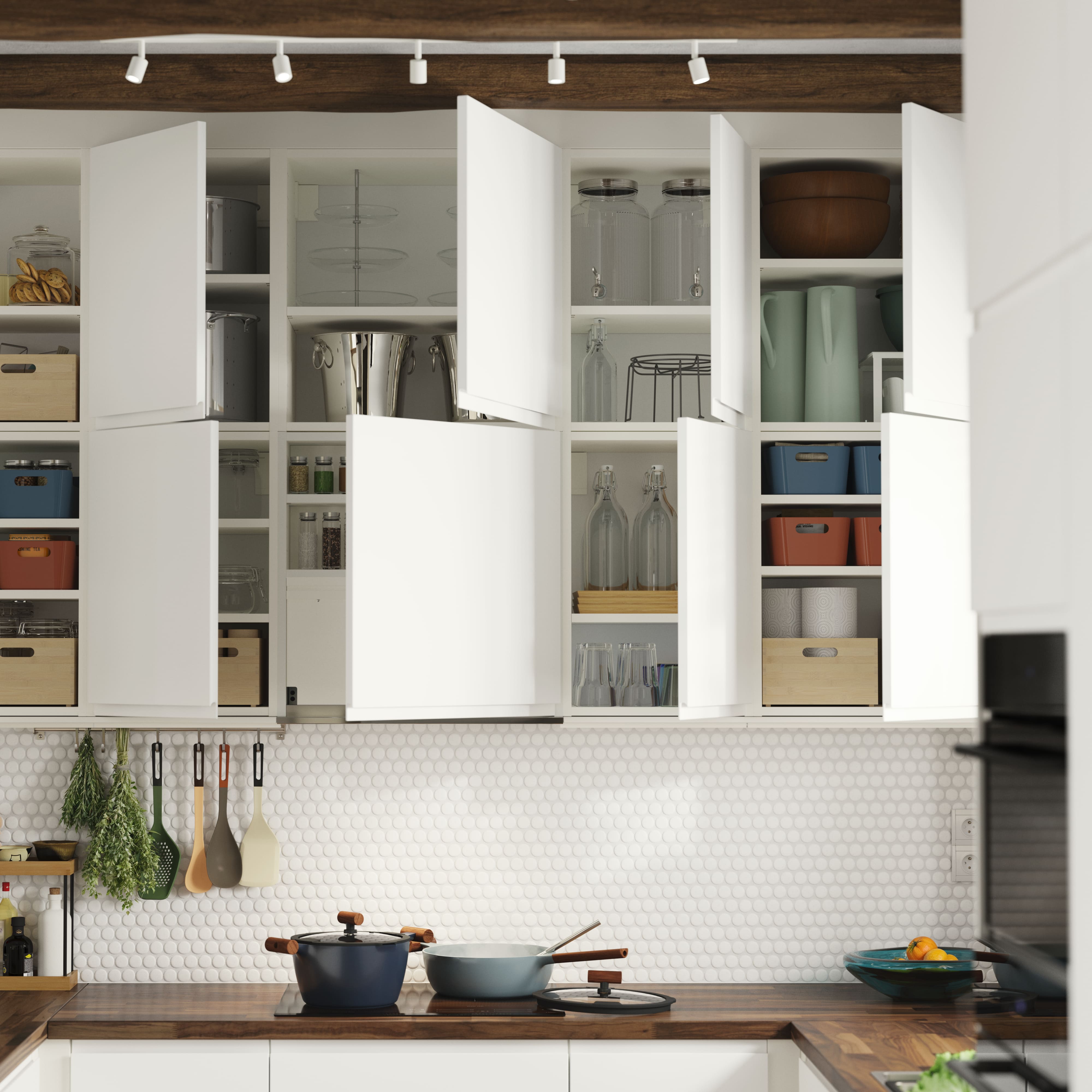 Open white kitchen cabinets displaying an organized arrangement of tableware, jars, and boxes above a dark wood countertop.