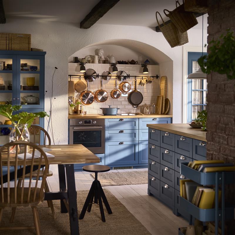 Rustic kitchen with blue cabinets and hanging cookware.