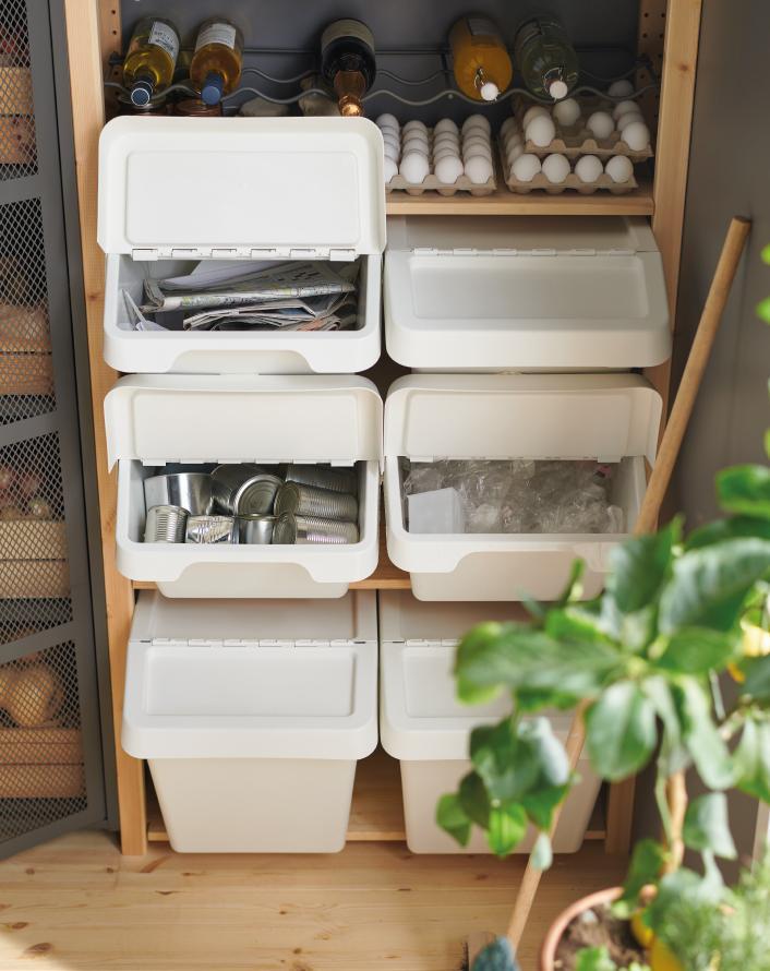 Cabinet with recycling system using white bins to separate paper, cans, and plastic.