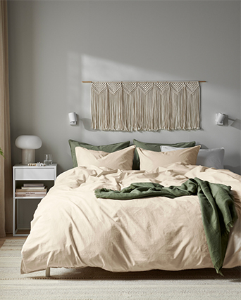 Close-up of a thick beige mattress with a side handle, resting on a minimalist white wooden bed frame.