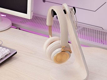 Auriculares inalámbricos de color beige con detalles dorados sobre un soporte de madera clara en un escritorio.
