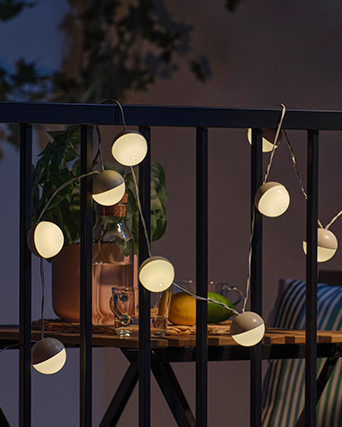 Las guirnaldas de luces LED SOLVINDEN iluminando una barandilla.
