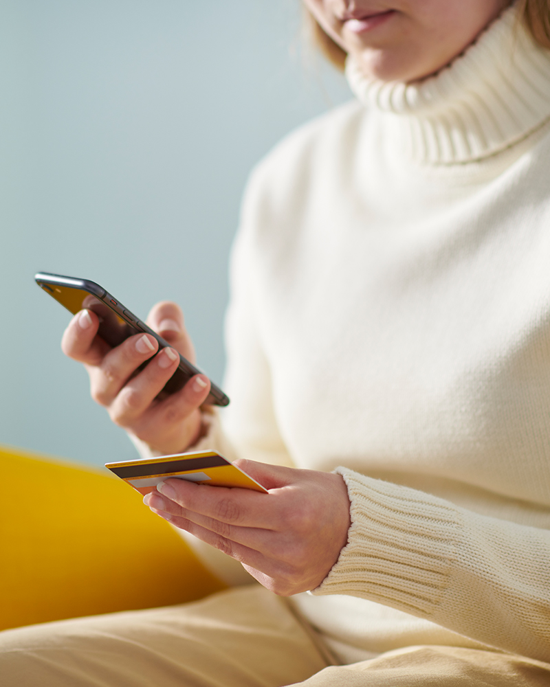 A woman entering her card details into her mobile phone to make an online purchase.